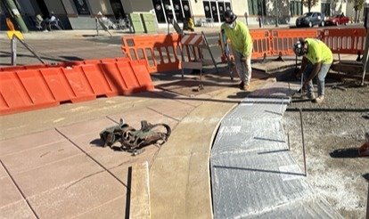 Construction along Grand Avenue featuring new sidewalk paving. 