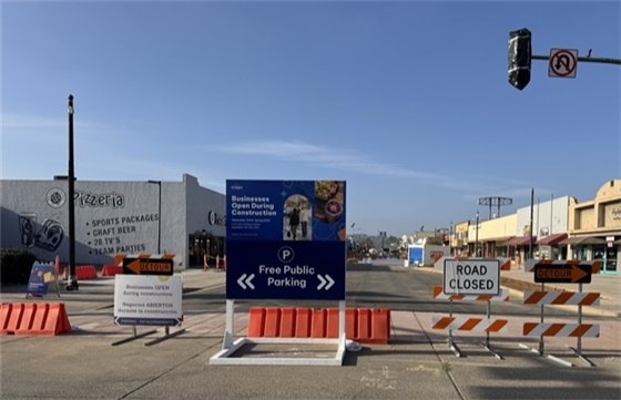 Construction along Grand Avenue: Traffic barrier and parking signage directing away from road closure. 