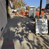 Pedestrain walkway with construction in main road. Sign reminding that businesses are open during contruction.
